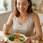 Adet Dönemi İçin Uzman Tavsiyesi: Hangi Yiyecekler Faydalı? 6 “Güneş ışığı alan mutfak masasında sağlıklı bir sebze ve tahıl kasesi hazırlayıp keyifle yiyen genç bir kadın.”